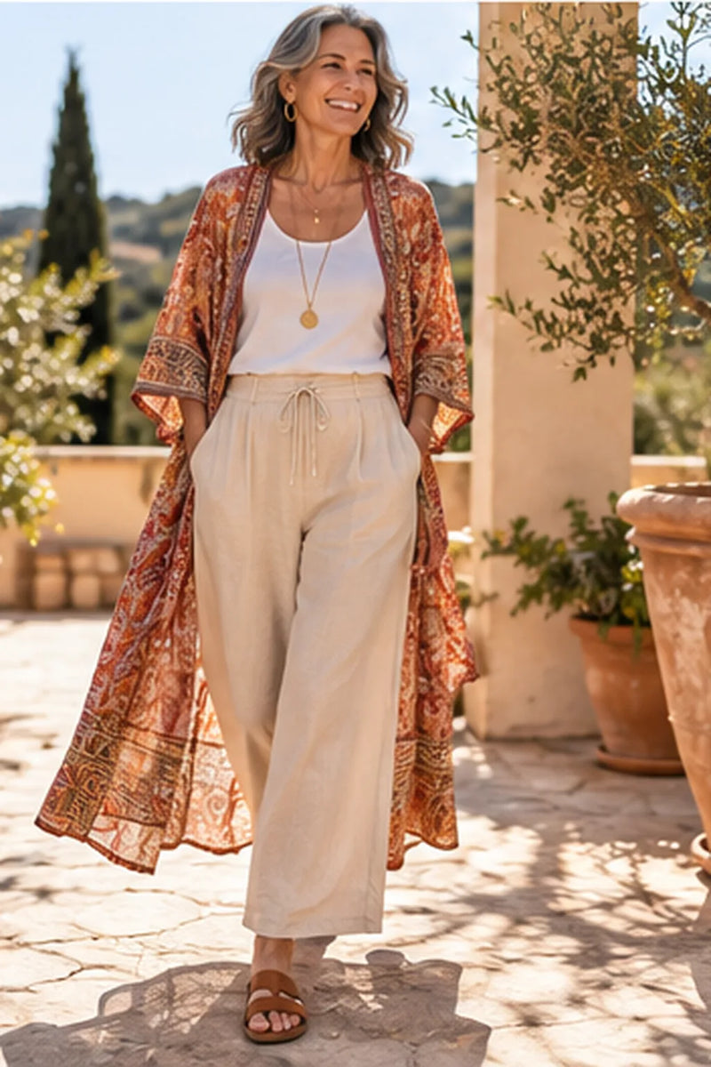 Boho Style ab 50: Frau im Kimono über weißem Top und Leinenhose mit langer Goldkette und Anhänger