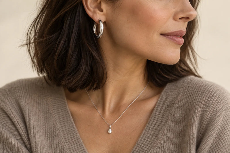 Schmuck zu mittellangen Haaren: silberne Creole und Silberkette mit Tropfenanhänger zum dunklen Long Bob