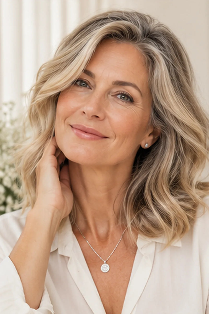 Balayage ab 50: schulterlanges Haar in Sand- und Champagnertönen mit eingebundenem Grau, dazu eine Silberkette
