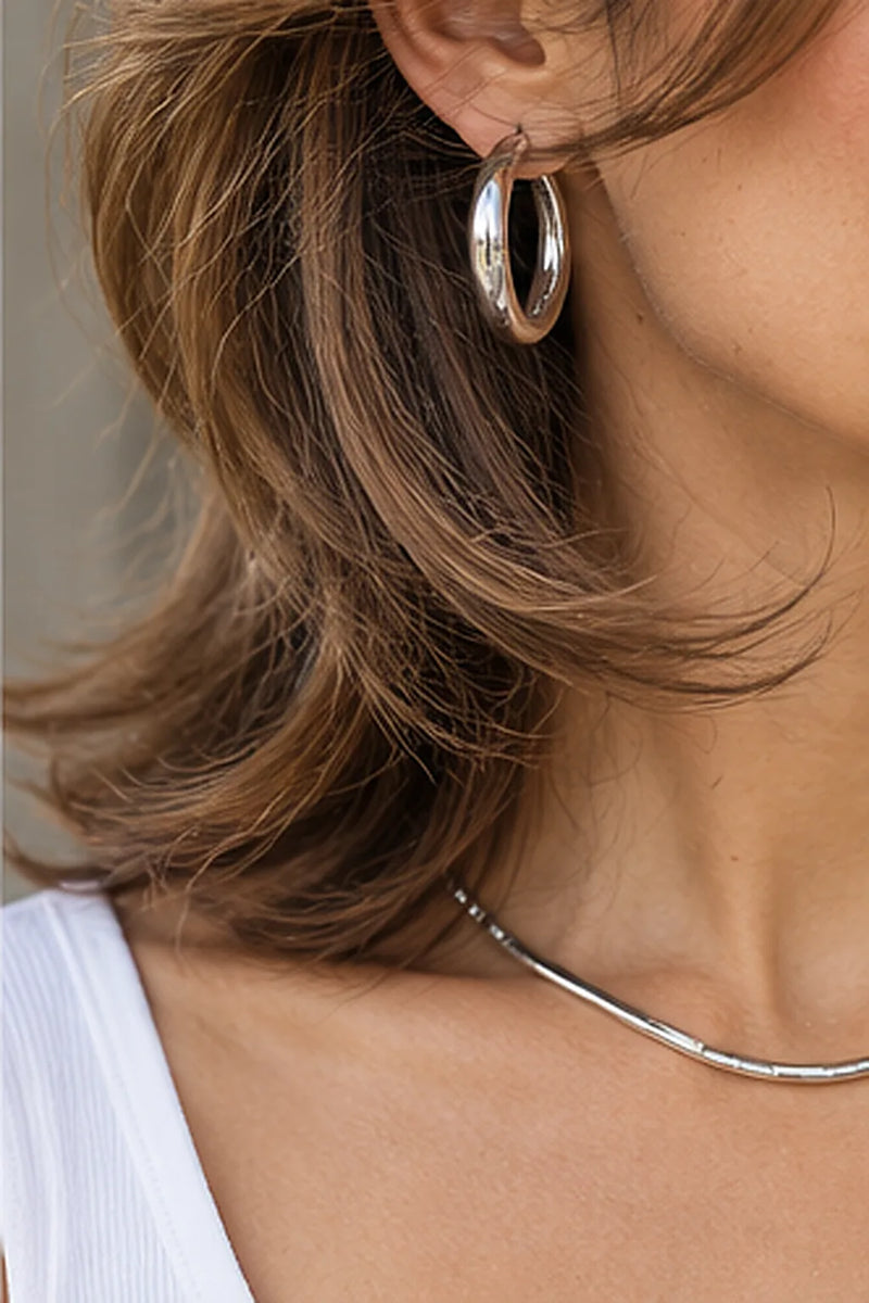Schmuck zum Butterfly Cut: silberne Creole und flache Silberkette zu gestuften braunen Haarspitzen